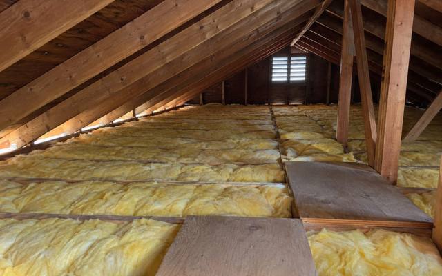 Yellow batts covering an attic floor with plywood boards laid across the joists as a walkway