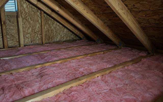 Pink fibreglass batts between joists in a small attic with an OSB gable wall and a vent