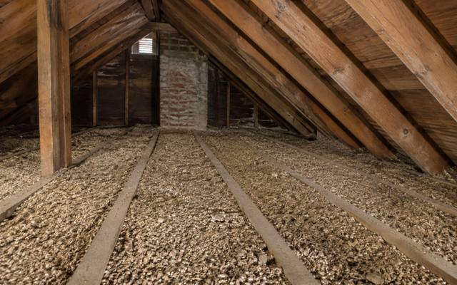 Old attic floor filled with pebbly grey-brown vermiculite between the joists
